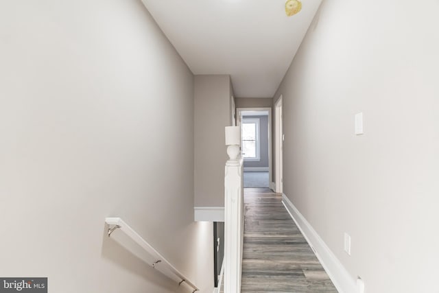 hall featuring baseboards, dark wood finished floors, and an upstairs landing