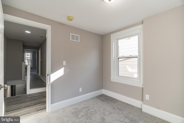 carpeted spare room with visible vents and baseboards