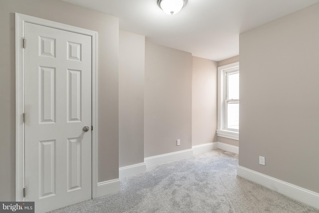 spare room with baseboards and light colored carpet