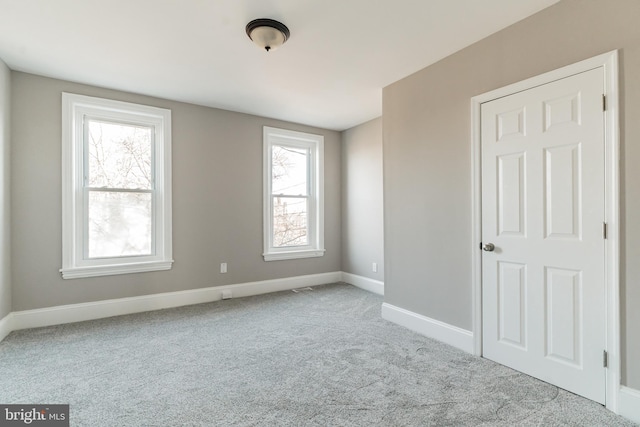 unfurnished room featuring light carpet and baseboards