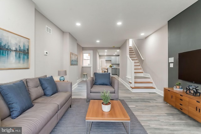 living area with light wood-type flooring, visible vents, recessed lighting, and stairs