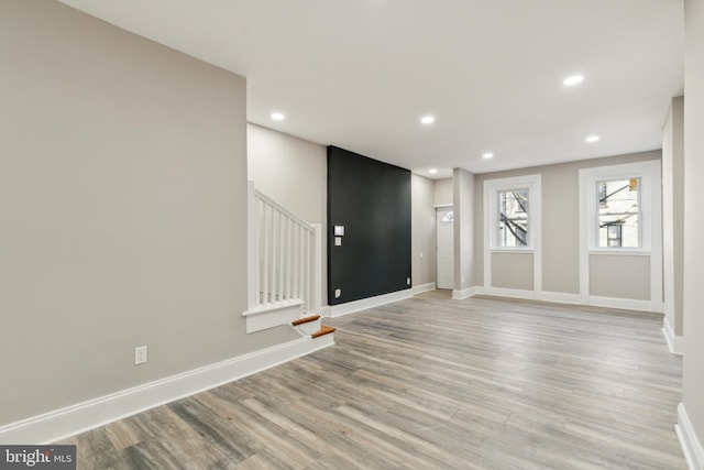 unfurnished room featuring light wood finished floors, baseboards, stairway, and recessed lighting