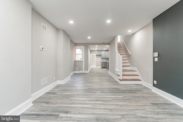 unfurnished living room featuring visible vents, light wood-style flooring, baseboards, and stairs