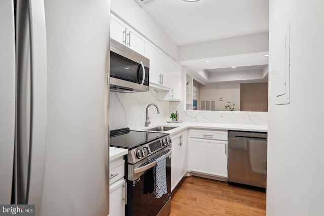 kitchen with sink, appliances with stainless steel finishes, backsplash, white cabinets, and light wood-type flooring