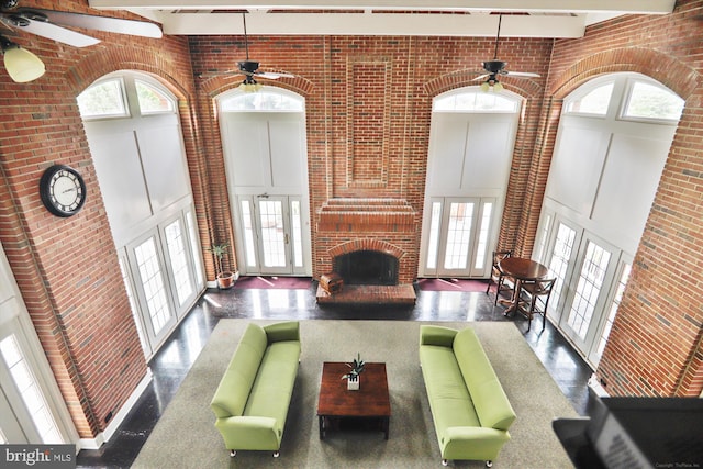 living room featuring a healthy amount of sunlight, brick wall, a brick fireplace, and a high ceiling