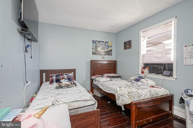 bedroom with a baseboard radiator, cooling unit, and dark hardwood / wood-style flooring