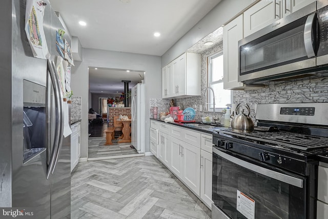 kitchen featuring light parquet floors, white cabinetry, appliances with stainless steel finishes, and sink