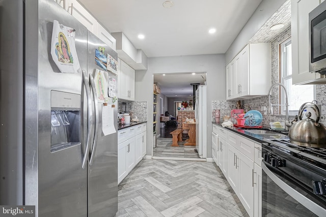 kitchen with stainless steel appliances, light parquet flooring, sink, and white cabinets