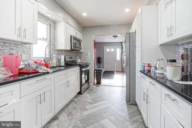 kitchen featuring sink, white cabinets, stainless steel appliances, decorative backsplash, and light parquet floors