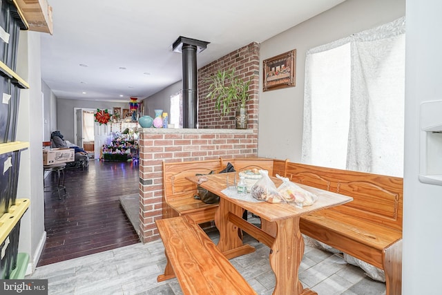 dining area with breakfast area, light wood-type flooring, and a wood stove