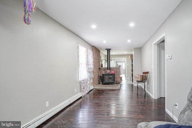 living room with a baseboard heating unit, dark hardwood / wood-style floors, and a wood stove