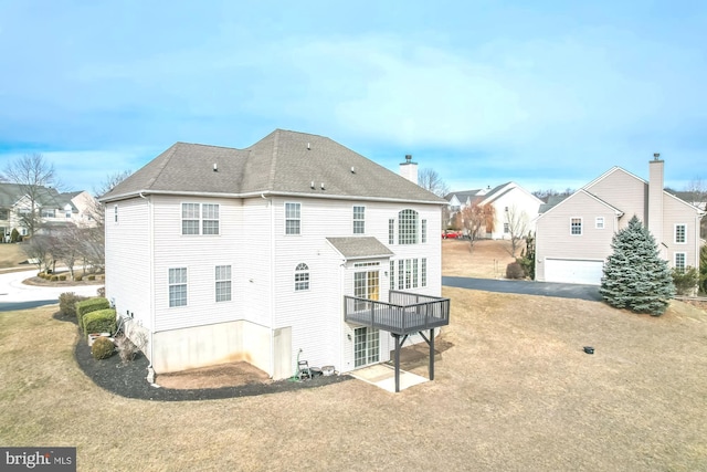 back of house featuring roof with shingles, a residential view, and a yard