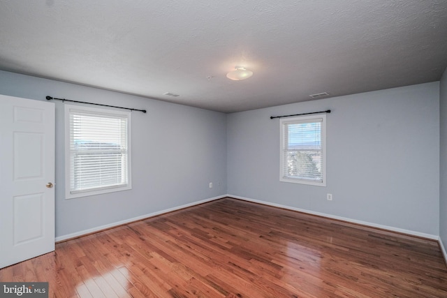 empty room featuring wood-type flooring and a textured ceiling