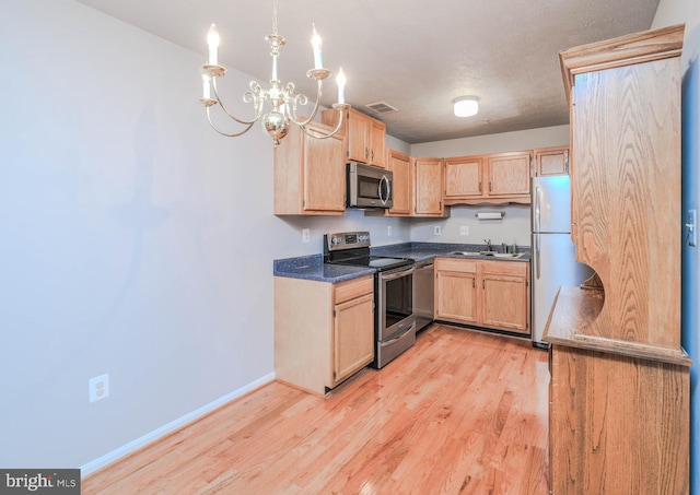 kitchen featuring a notable chandelier, light wood-type flooring, light brown cabinets, and appliances with stainless steel finishes