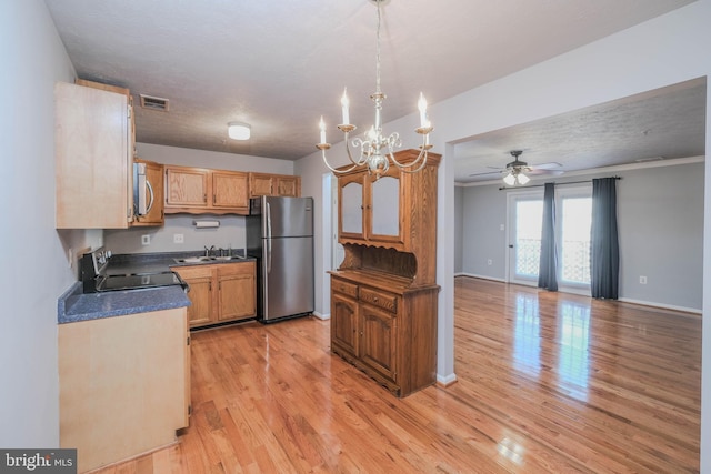 kitchen featuring ceiling fan with notable chandelier, stainless steel appliances, sink, and light wood-type flooring