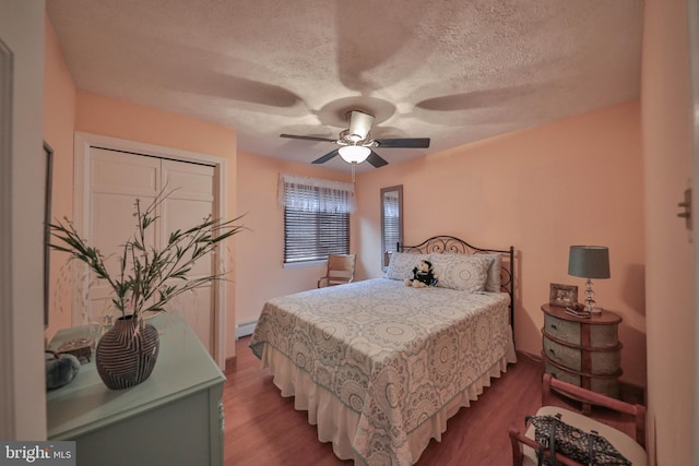 bedroom featuring baseboard heating, ceiling fan, hardwood / wood-style floors, and a textured ceiling