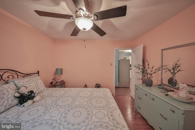 bedroom with ceiling fan, stainless steel fridge, and dark hardwood / wood-style flooring