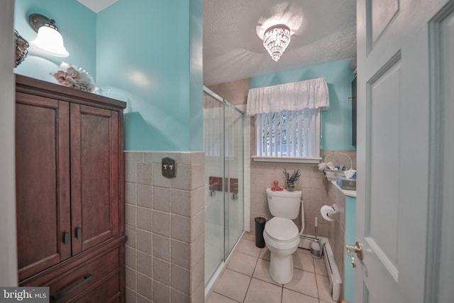 bathroom featuring baseboard heating, tile patterned flooring, a textured ceiling, and tile walls