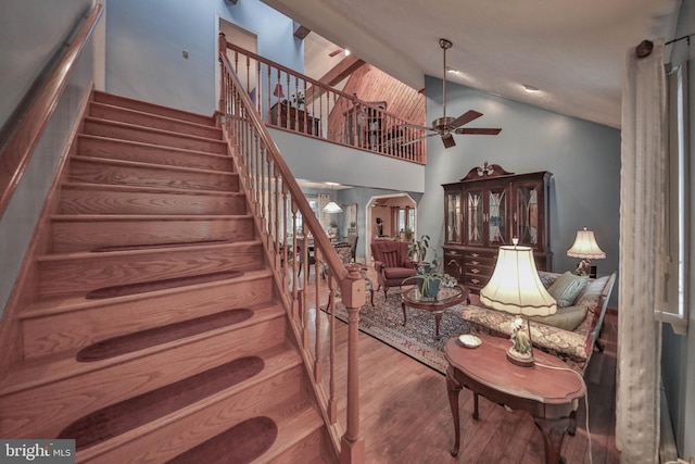 stairs featuring high vaulted ceiling, hardwood / wood-style floors, and ceiling fan