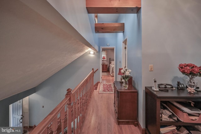 corridor with beamed ceiling and light hardwood / wood-style flooring