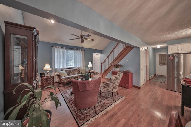 living room featuring lofted ceiling, ceiling fan, and light hardwood / wood-style flooring