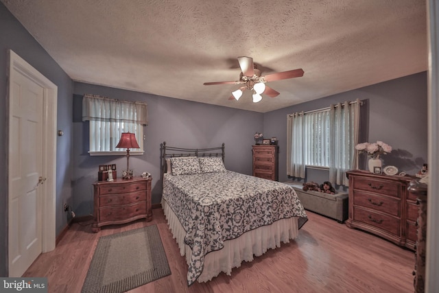 bedroom featuring hardwood / wood-style flooring, a textured ceiling, and ceiling fan