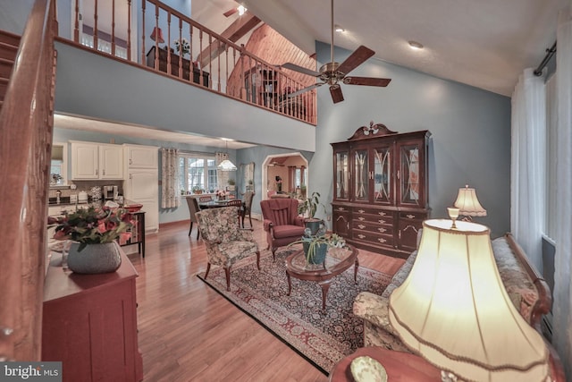 living room featuring ceiling fan, high vaulted ceiling, and light hardwood / wood-style floors