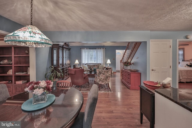 dining room with wood-type flooring and a textured ceiling