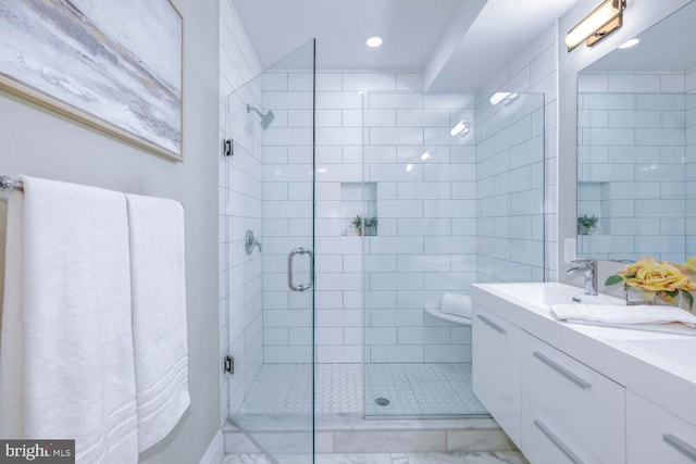 bathroom featuring a shower with door and vanity