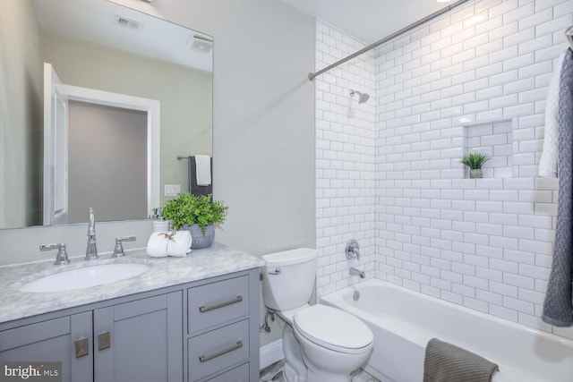 full bathroom with tiled shower / bath combo, vanity, and toilet