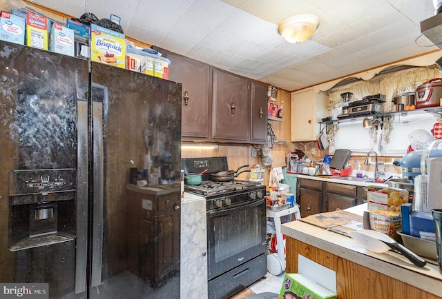 kitchen with black appliances, dark brown cabinets, a sink, and light countertops