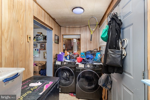 laundry room featuring wooden walls, light floors, laundry area, and washer and dryer