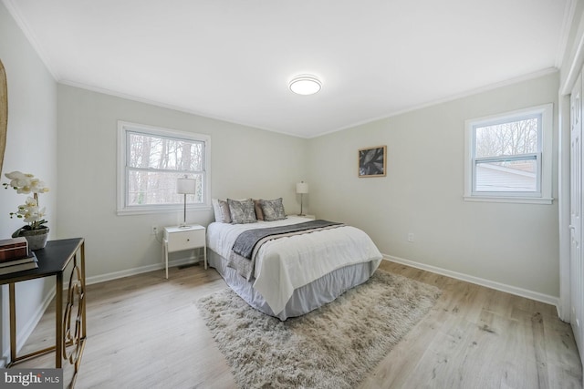 bedroom with multiple windows, light wood-style flooring, and baseboards