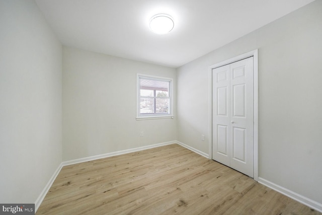 unfurnished bedroom with a closet, baseboards, and wood finished floors