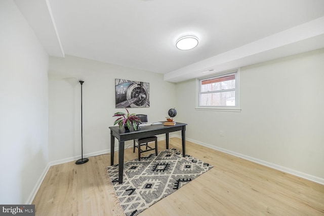 office space with light wood-style floors, visible vents, and baseboards