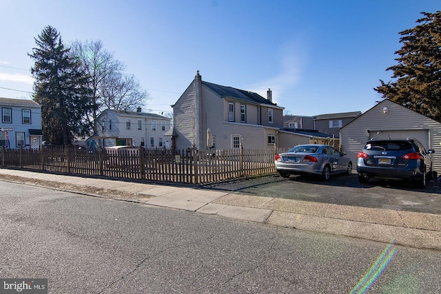 view of front facade with a garage, a fenced front yard, a residential view, and an outbuilding