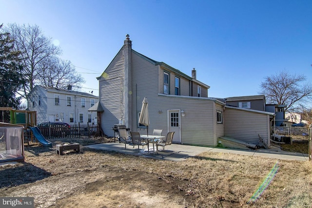 back of property with a patio area, fence, a chimney, and a playground