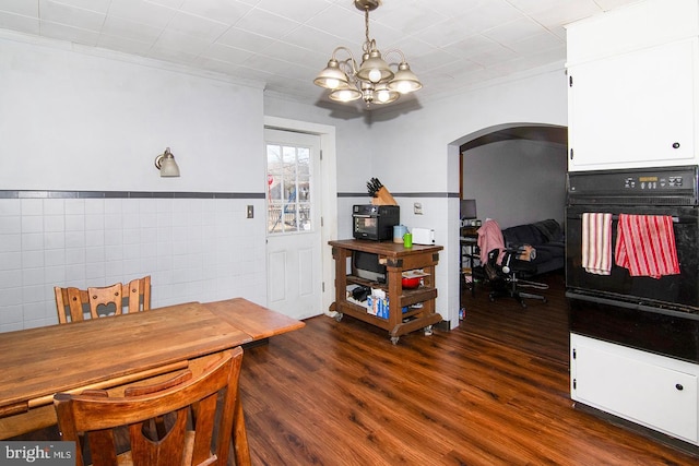 dining space with an inviting chandelier, arched walkways, dark wood-style flooring, and ornamental molding