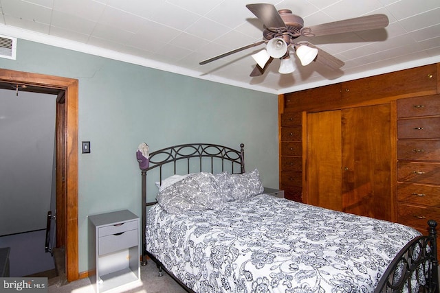 carpeted bedroom with ornamental molding, a closet, and a ceiling fan