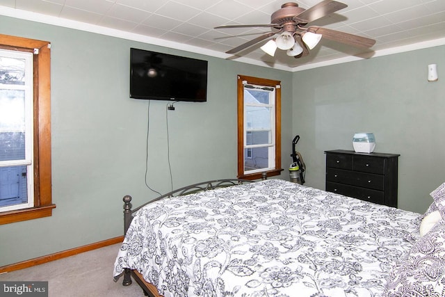 bedroom with ornamental molding, carpet, a ceiling fan, and baseboards