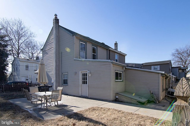 back of property with a chimney, fence, and a patio