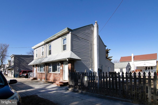 view of home's exterior with brick siding, fence, and a chimney