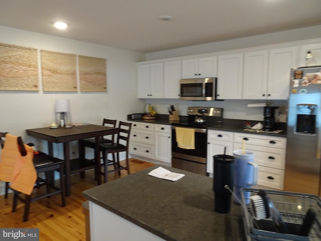 kitchen with hardwood / wood-style flooring, appliances with stainless steel finishes, and white cabinets