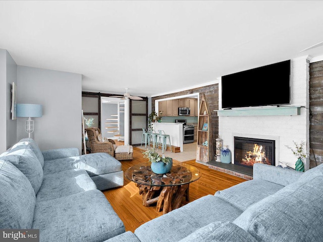 living room featuring a barn door, hardwood / wood-style floors, and a brick fireplace