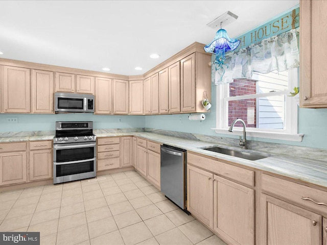 kitchen featuring light tile patterned flooring, appliances with stainless steel finishes, decorative light fixtures, sink, and light brown cabinets