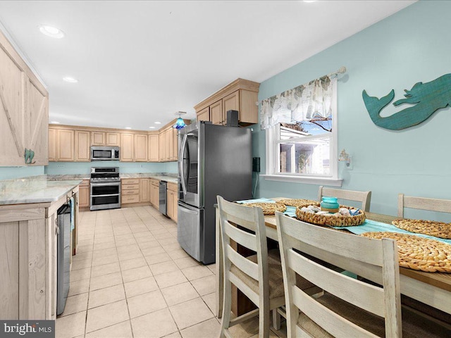 kitchen with appliances with stainless steel finishes, light tile patterned floors, and light brown cabinetry