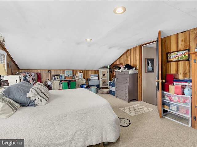 bedroom featuring carpet floors, wooden walls, and vaulted ceiling