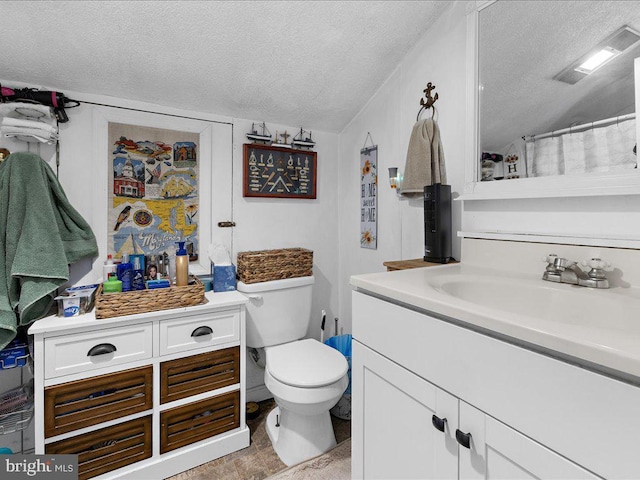 bathroom with vanity, toilet, and a textured ceiling