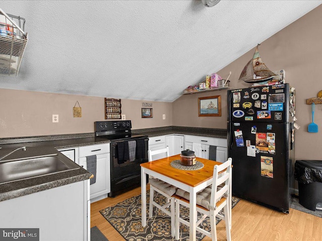 kitchen featuring light hardwood / wood-style flooring, black appliances, white cabinets, and vaulted ceiling