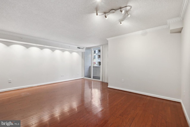 unfurnished room featuring wood-type flooring, ornamental molding, a textured ceiling, and track lighting